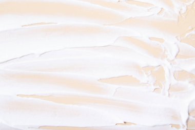 Bej arkaplanda beyaz krem fırça darbeleri üst görünüm.