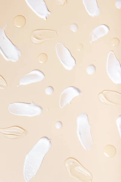 Pattern of brush strokes and drops of cosmetic oil and serum top view on beige. .background.