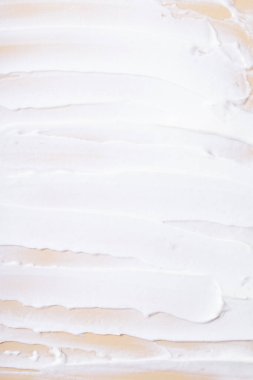 Bej arkaplanda beyaz krem fırça darbeleri üst görünüm.