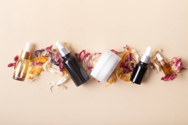 Kozmetik şişeleri ve kavanozla bej arka plan görünümlü kuru renkli çiçek yaprakları..