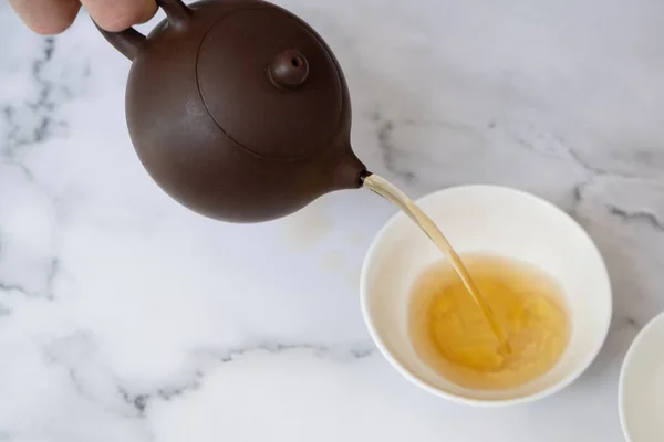 O chá do bule é derramado em uma xícara. Conceito de cerimônia de chá — Fotografia de Stock