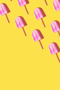 Parlak açık sarı arka planda pembe dondurmayla yapılan son moda güneş ışığı deseni. Asgari yaz konsepti.