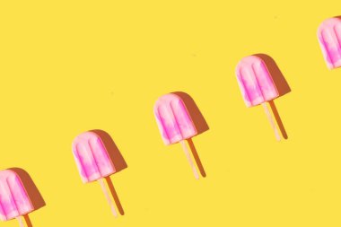 Parlak açık sarı arka planda pembe dondurmayla yapılan son moda güneş ışığı deseni. Asgari yaz konsepti.
