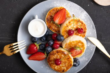 Yakın plan kavrulmuş peynirli kekler, pudra şekeri ve böğürtlenli tabakta..