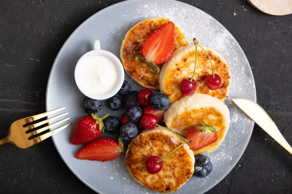 Yakın plan kavrulmuş peynirli kekler, pudra şekeri ve böğürtlenli tabakta..