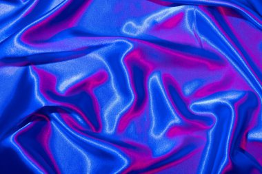 Tekstil, neon mavi-pembe ışıkta katlanır. Moda renkleri ve parlak soyut arkaplan.