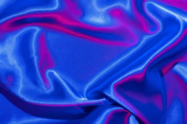 Tekstil, neon mavi-pembe ışıkta katlanır. Moda renkleri ve parlak soyut arkaplan.