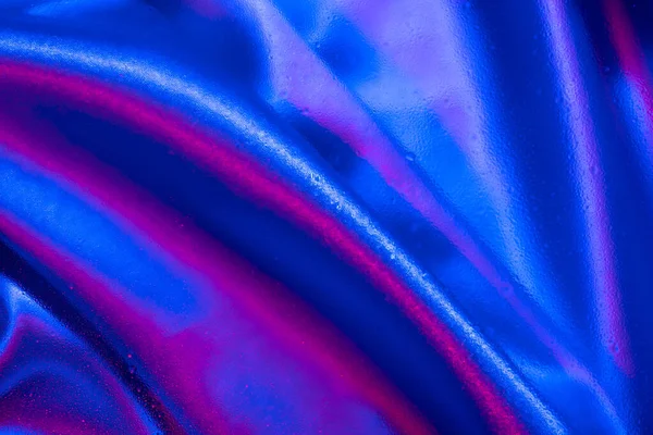 Cam altında tekstil ve neon ışıkta su damlaları. Moda renkleri ve parlak arkaplan.