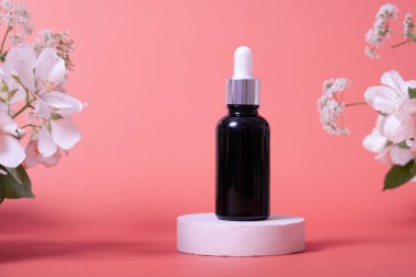 Kozmetik cam damlası şişesi, yağ, serum ya da yasemin çiçekleriyle podyumda soyulan meyve. Doğal arka planda güzellik ürünü sunumu. Ön manzara. Model konsepti.