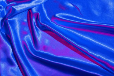 Tekstil, neon mavi-pembe ışıkta katlanır. Moda renkleri ve parlak soyut arkaplan.