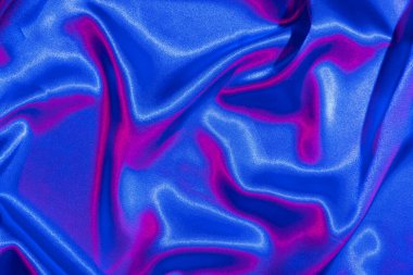 Tekstil, neon mavi-pembe ışıkta katlanır. Moda renkleri ve parlak soyut arkaplan.