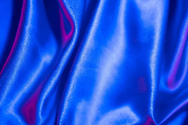 Textiles under glass with drops of water in neon light. Trendy colors and shiny background.