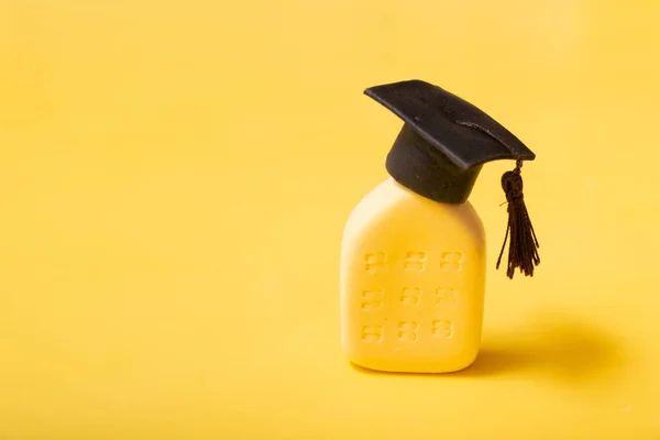 Graduate hat on the abstract building. Educational institution concept. Yellow background with copy space.