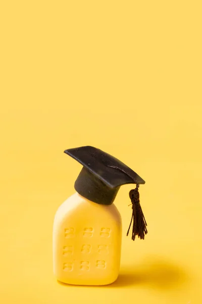 Graduate hat on the abstract building. Educational institution concept. Yellow background vertical format.
