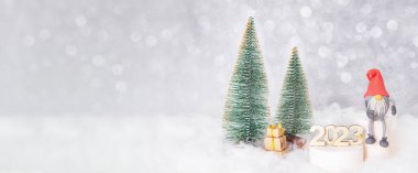 Yeni Yıl 2023 kompozisyonu ile afiş Noel ağaçları, kar ve kaidede 2023 numara.