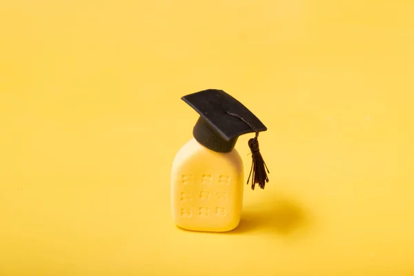 Graduate hat on the abstract building. Educational institution concept. Yellow background