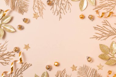 Yılbaşı ya da yeni yıl kompozisyonu. Pastel bej arka planda altın rengi Noel süsleri ve karşılama için boş kopya alanı.