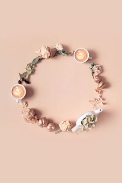 Autumn composition. Wreath made of dried leaves and coffee cups on pastel beige background. Autumn, fall concept. Flat lay, top view, copy space.
