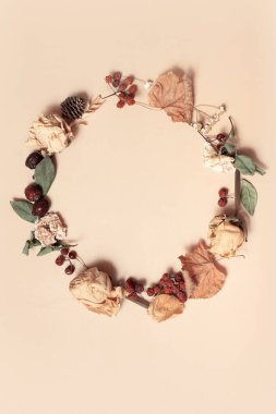 Sonbahar kompozisyonu. Pastel bej arka planda kurumuş yapraklardan yapılmış çelenk. Sonbahar, sonbahar konsepti. Düz konum, üst görünüm, kopyalama alanı.