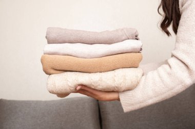 Kanepe arkasında kadın ellerine örülmüş bir yığın süveter. Sıcak konsept.