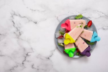 Tabaktaki plastik kalıplardan dondurma ve mermer masa arkasında buz. Üst Manzara. Boşluğu kopyala.