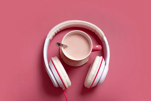 Creative flat lay composition with cocoa cup and headphones on dark pink color background. Creative music, relax, online concept.