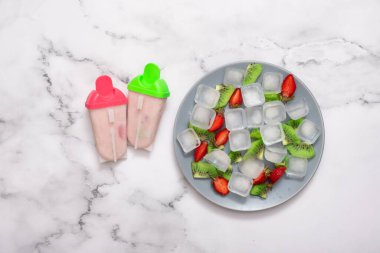 Plastik kalıplı ev yapımı dondurmanın ve buzlu bir tabağın ve meyve parçalarının en üst görüntüsü..