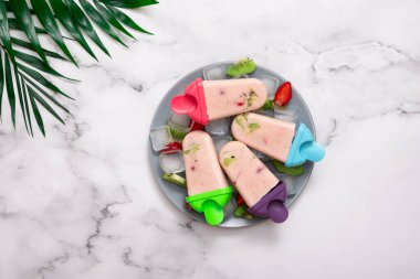 Plastik kalıptan dondurma, buz, meyve ve palmiye yaprakları. Üst görünüm.