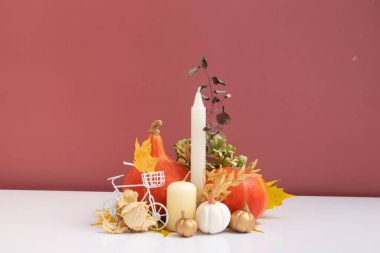 Sonbahar kompozisyonu. Beyaz pembe arka planda kurumuş yapraklar, balkabakları ve mumlar. Sonbahar ve Şükran Günü konsepti. Durgun hayat.