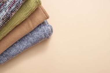 Bej arka planda örülmüş bir kazak yığını. Sıcak konsept.