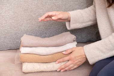 Kadın elleri kanepede rahat örülmüş kazaklar dizer. Sıcak konsept.