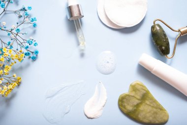 Renkli arka planda yüz masajcısı olan serum ve nemlendirici makyaj kremi. Üst görünüm.