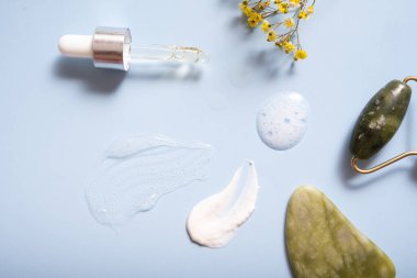 Renkli arka planda yüz masajcısı olan serum ve nemlendirici makyaj kremi. Üst görünüm.