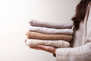 Bej arka planda, kadın ellerine örülmüş bir yığın kazak. Sıcak konsept.