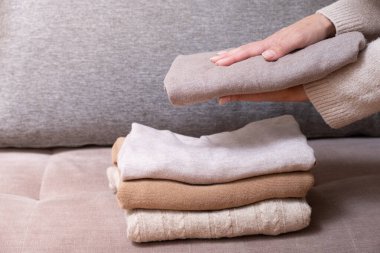 Kadın elleri kanepede rahat örülmüş kazaklar dizer. Sıcak konsept.