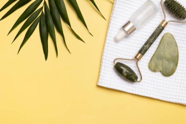 Yeşim taştan masöz, kozmetik yağ ve havluyla güzellik masajı için. Sarı arka planda düz uzandı.