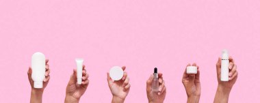 Female hands with different cosmetic products in container and bottles on pink color background.