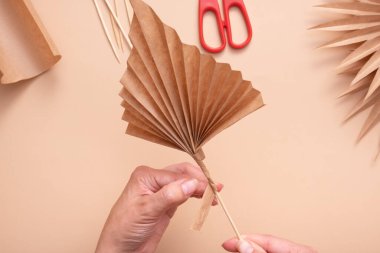 Wrapping the trunk of the leaf with a glued strip of paper. Creative handwork to create tropical leaves. Master class.