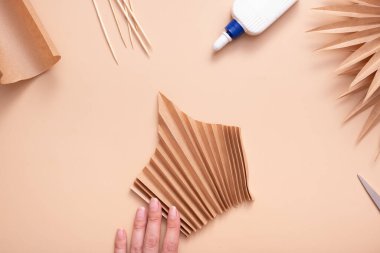 The accordion-folded paper blank is ready for gluing. Creative handwork to create tropical leaves. Master class.