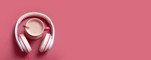 Creative flat lay composition with cocoa cup and headphones on dark pink color background. Creative music, relax, online concept.