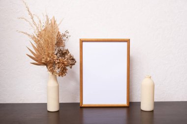 Mock up empty wooden frame mockup, dried leaf and pampass grass in vase on white background, interior, home design. Art concept. copy space.