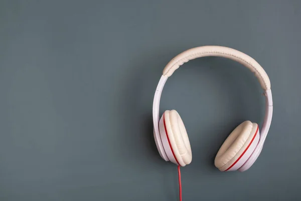 White-colored headphones on dark blue-green background. Minimalistic fashion music concept. Copy space. Top view, flat lay.