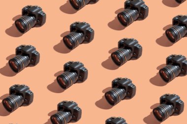 Pattern from many cameras on orange color background. World Photography Day concept.