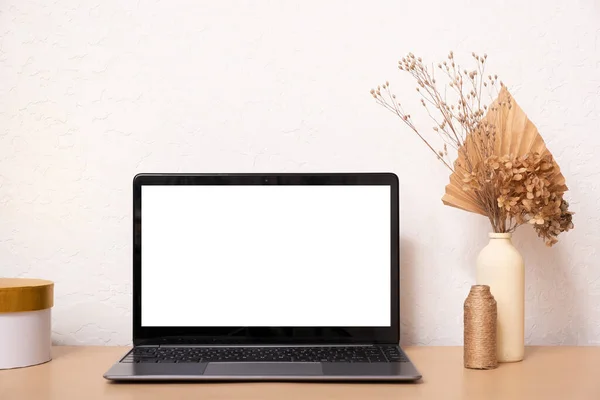 Laptop computer with blank screen, dried grass bouquet and vases. Aesthetic influencer boho styled interior design template with mockup laptop, copy space.