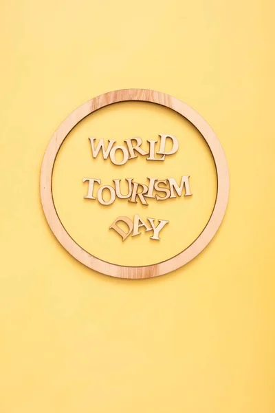 World Tourism Day text from wooden letters on a yellow background with round frame. High quality photo