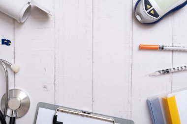 Glucometer, stethoscope and syringes with a tablet on a wooden background, top view. Copy space. High quality photo