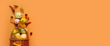 Autumn banner with harvest basket with corn, apples, zucchini and peppers on a orange background top view