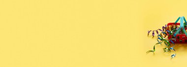 Renkli bir arka planda, üzerinde süs ve çanta bulunan bir alışveriş sepeti. Boşluğu kopyala