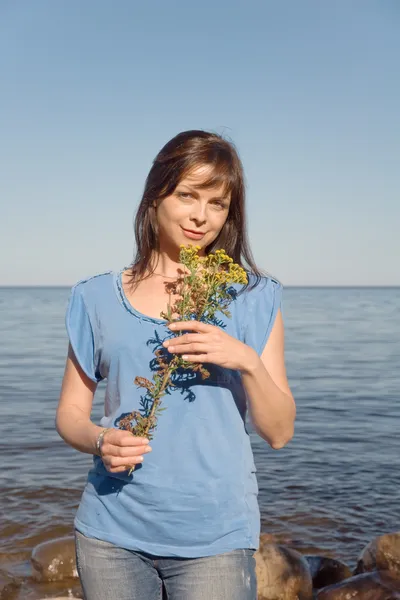 Vacker kvinna med gula blommor på sjön. — Stockfoto