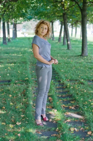 Vacker kvinna gå i en grön park. solig dag — Stockfoto